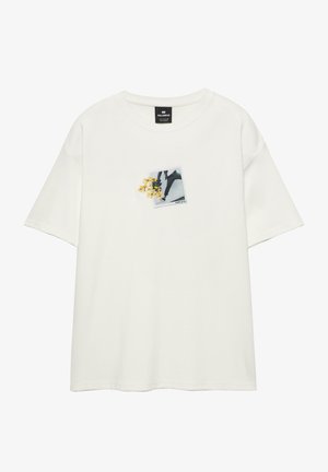 Bijela kratki rukav T-shirt s malim grafičkim prikazom nečijih nogu koje hodaju i žutim cvjetovima na lijevoj strani prsnog dijela.