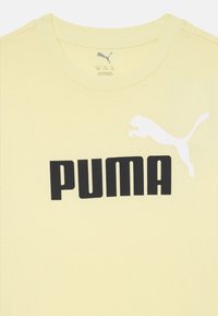 Gul bomull t-skjorte med rund hals, med en stor svart "PUMA" logo og en hvit springende puma-grafikk på venstre side.
