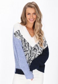 Sweter z dekoltem w serek o teksturowanym splocie, z niebieskimi i granatowymi sekcjami oraz wzorem z cekinami w centrum. Miękki materiał o luźnym kroju.