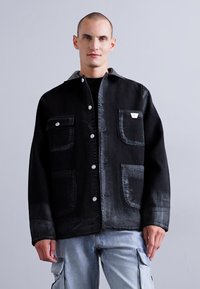 Črna denim jakna z dvema sprednjima žepoma, srebrnimi gumbi in nekoliko zbledelim videzom. Načrtovana s klasičnim ovratnikom in ravnim krojem.