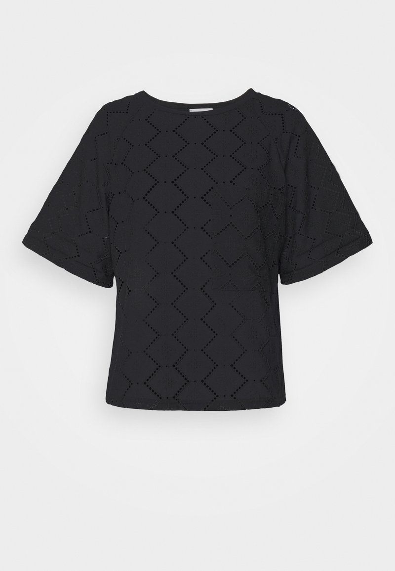 Blouse noire à manches courtes avec motifs découpés en zigzag et col rond, présentée sur un fond clair uni.