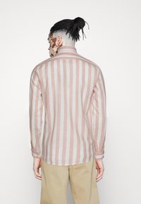 Långärmad skjorta i ljusrosa och vita ränder, med krage och knappmanschetter, tillverkad av lätt tyg och med en avslappnad passform.