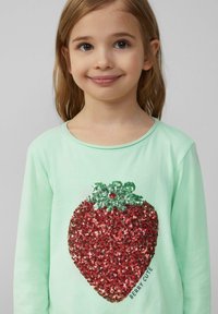 Mintgroene lange mouw shirt met een groot rode sequins aardbei ontwerp met groene accenten en de tekst "BERRY CUTE" in zwart.
