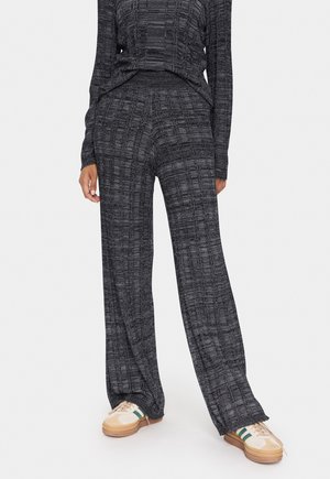 Ensemble de détente tricoté noir et gris à motifs, avec des manches longues et un pantalon large ; tissu texturé et coupe décontractée.