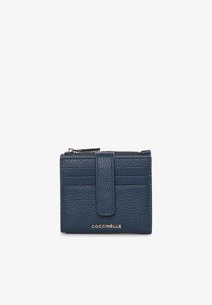 Compact, gestructureerde portemonnee van donkerblauw leer met meerdere kaartsleuven, een drukknoopriem, een ritsvak en een metalen "COCCINELLE"-logo.