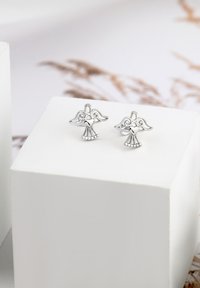 Silverfärgade änglaskingformade örhängen med hjärtdetalj och dekorativa vingar, med en slät finish och små pärlaccenter vid basen.