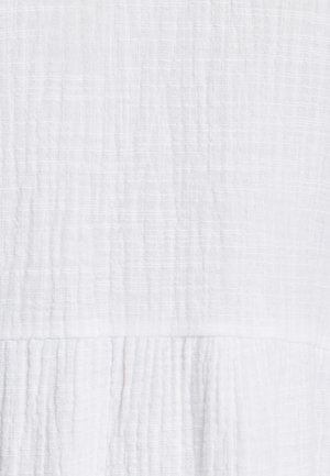 Tekstūrēts balts audums ar sagrumbuļu rakstu. Materiāls ir viegls un mīksts, ar nelielu kontrastu virsmas detaļās.