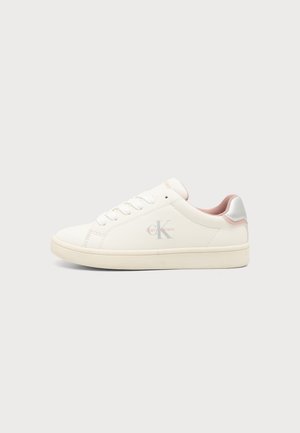 Λευκό sneaker χαμηλής κοπής με ροζ εσωτερική επένδυση, μπροστινό δέσιμο με κορδόνια και λογότυπο Calvin Klein στο πλάι πάνω σε ανοιχτό γκρι φόντο.