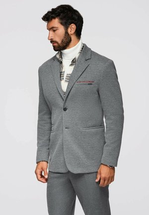 Grauer Blazer mit taillierter Passform, aus weichem Stoff gefertigt, mit zwei Vordertaschen und einem dezenten roten Akzent auf der Brusttasche.