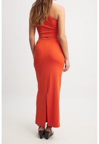 Rød gulvlængde kjole med en skulderrem, tætsiddende design og en slids bagtil. Fremstillet af glat stof, der fremhæver en slank silhuet.