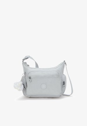 Lichtgrijze nylon crossbodytas met verstelbare riem, voorvak met ritssluiting, cirkelvormig logo en een pluizige witte hanger eraan bevestigd.