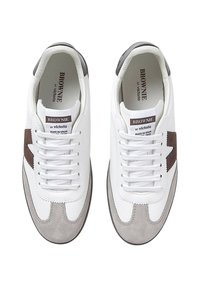 Zapatillas de cuero blancas con detalles en gamuza gris, diseño en forma de estrella marrón y cordones planos blancos. Etiqueta "BROWNIE" visible en el interior del zapato.