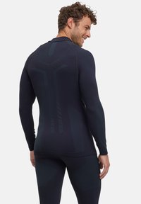 Aansluitend langshirt met lange mouwen in donker marineblauw, gemaakt van soepel rekbaar materiaal. Bevat textuurpanele en ergonomische naden voor verbeterde bewegingsvrijheid.