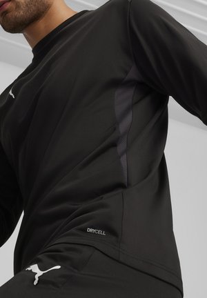 Zwart sportshirt met lange mouwen, gemaakt van vochtregulerende stof met een gestructureerd zijpaneel. Het shirt heeft een subtiele logo en "DRYCELL" detail.