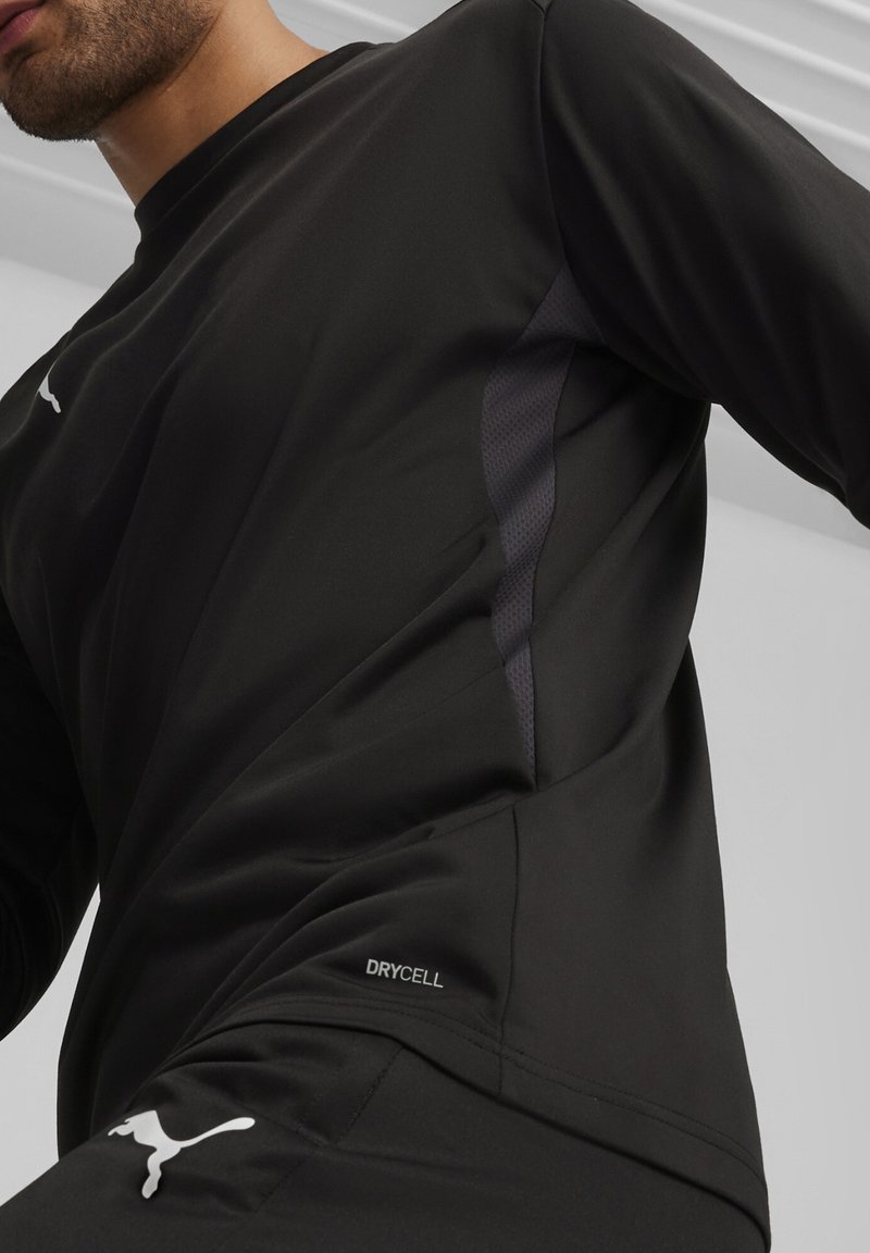 Zwart sportshirt met lange mouwen, gemaakt van vochtregulerende stof met een gestructureerd zijpaneel. Het shirt heeft een subtiele logo en "DRYCELL" detail.
