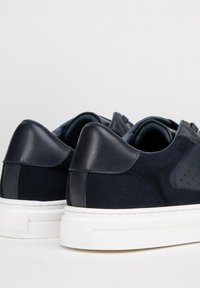 Granatowe trampki z zamszowymi i skórzanymi akcentami, solidna biała gumowa podeszwa, zaokrąglony kształt oraz perforowane detale po bokach.