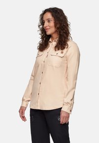 Helles beige Langarmhemd mit zwei Brusttaschen, knopfbarem Frontverschluss und braunen Knöpfen. Glatte Textur mit lässiger Passform.
