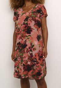 Robe florale avec un décolleté en V et des manches courtes. Dotée d'une base rose clair avec des motifs de fleurs rouges et noires. Conception légère et coupe ample.