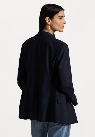 Löydä rakenteellinen muotoilu, johon kuuluu sininen bleiseri, yksinkertainen takaventtiili ja hillitty kiilto. Varustettu kahdella sivutaskulla ja kontrastivärisillä kultaisilla yksityiskohdilla.