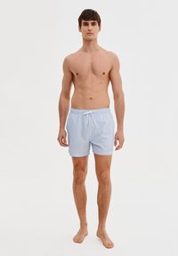 Niebieskie i białe paskowane szorty kąpielowe z elastycznym pasem i sznurkiem do regulacji, wykonane z lekkiego materiału, o luźnym kroju.