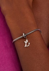 Zilveren armband met een flexibel ontwerp, voorzien van een hanger in de vorm van een 'L' charme, gezet met een kleine edelsteen. Gladde textuur om de pols.