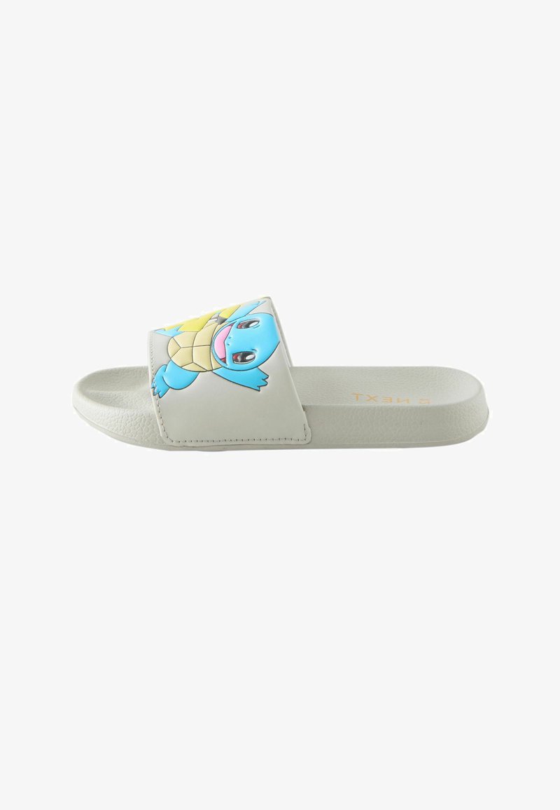 Sandale à glissière blanche avec un personnage de tortue bleue en dessin animé sur la bride et une semelle texturée, vue de côté.
