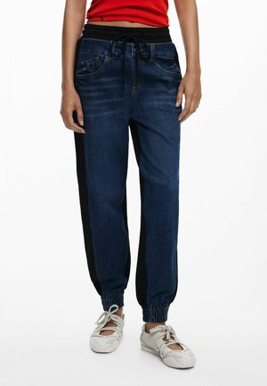 Denim joggers with a dark blue wash, black side panels, elastic cuffs, and an adjustable drawstring waistband. Features front pockets.