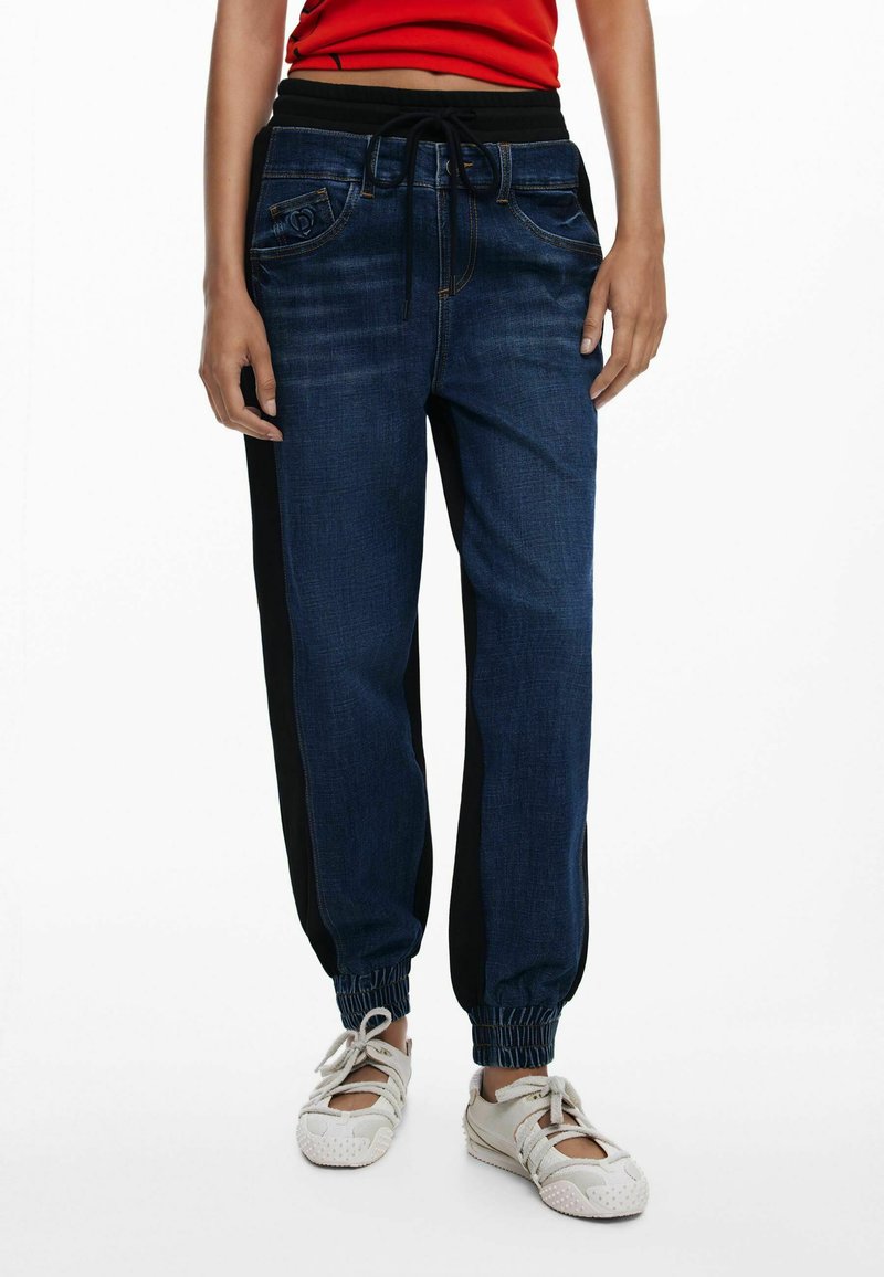 Denim joggers met een donkerblauwe wassing, zwarte zijpanelen, elastische boorden en een verstelbare trekkoord tailleband. Voorzien van voorzakken.