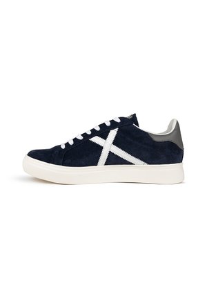 Sneaker in suede blu navy con design incrociato in suede bianco, lacci bianchi, tallone grigio e suola in gomma bianca testurizzata. Vista laterale mostrata.