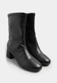 Czarne skórzane botki za kostkę z kwadratowym noskiem i masywnym obcasem. Cechują się gładką teksturą oraz starannym szyciem wzdłuż górnej krawędzi.