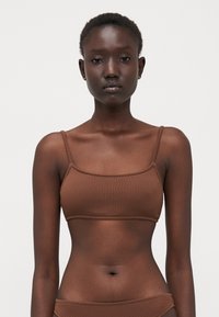 Brown textured bralette with thin straps and a square neckline, featuring a smooth, stretchy fabric and a seamless design.