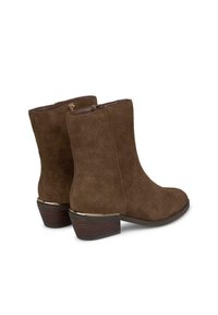Braune Wildleder-Stiefeletten mit runder Zehenform, einem dezenten Blockabsatz und einem goldfarbenen Akzent an der Sohle. Mit seitlichen Reißverschlüssen für ein einfaches An- und Ausziehen.