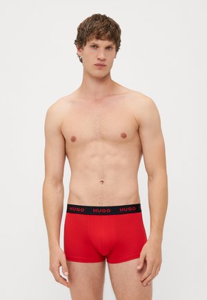 Piros pamut boxer short, fekete gumis derékkal, amelyen a "HUGO" logó látható. Az anyag sima és testhezálló.