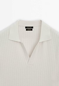 Lysegrå strikket pullover med ribbet tekstur, der har en placket krave og en V-hals design. Etiketten er synlig inde i halsudskæringen.