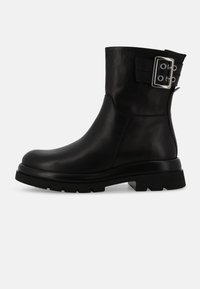 Stivale alla caviglia in pelle nera con punta rotonda, suola spessa e dettaglio in fibbia argentata sul lato. Texture liscia con design robusto.