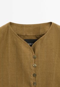 Bruine blouse met verticale strepen, V-hals, vijf knopen en een gestructureerde stof. Label zichtbaar aan de binnenkant van de kraag.
