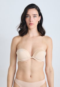 Sutiã nu sem alças com tecido liso, copas contornadas e fecho de gancho. Apresenta um design sem costuras e discretos detalhes de marca.