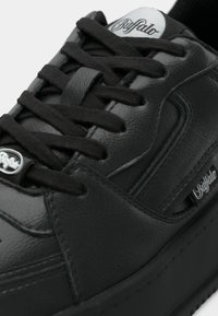 Μαύρο δερμάτινο αθλητικό παπούτσι με λεία υφή, στρογγυλερή μύτη, επίπεδα μαύρα κορδόνια και εμφανή ετικέτα με λογότυπο στην πλευρά.