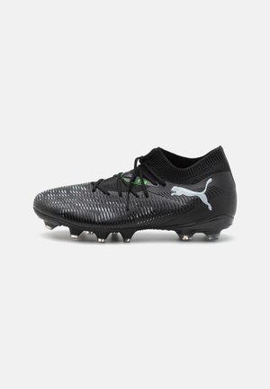Bota de fútbol negra Puma con parte superior texturizada, cierre de cordones, cuello tipo calcetín y logo plateado de Puma en el lateral, sobre fondo blanco.