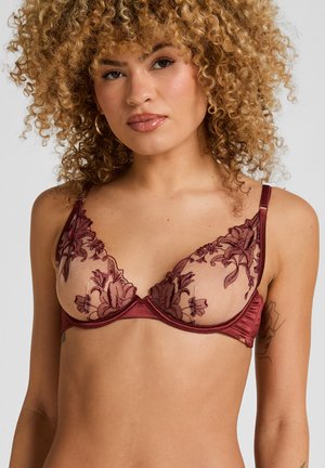 Bordeauxfarbener Spitzen-BH mit floraler Stickerei auf transparenten Cups, Satinband, verstellbaren Trägern und Bügelunterstützung; filigrane Details deutlich sichtbar.