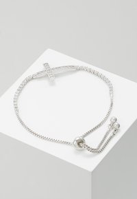 Sidabrinė apyrankė su kryžiumi, akcentuota skaidriais kristalais, turinti slystančią karoliukų užsegimą ir du perlamutriniai galai, leidžiantys reguliuoti dydį.