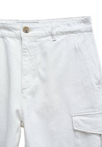 Pantalones cargo blancos con cierre de botón, bolsillos laterales y tejido texturizado. El diseño incluye un corte recto y detalles cosidos.