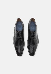 Scarpe eleganti in pelle nera con design a brogue, punta appuntita, chiusura con lacci e finitura liscia con dettagli perforati.