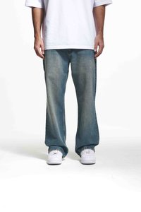 Jeans din denim de un albastru deschis cu un croi relaxat și picioare largi, având un fading subtil și detalii de cusătură, asortați cu adidași albi.
