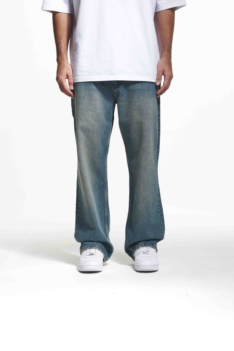 Jeans din denim de un albastru deschis cu un croi relaxat și picioare largi, având un fading subtil și detalii de cusătură, asortați cu adidași albi.
