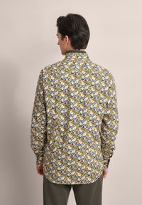 Langärmliges Hemd mit floralem Muster in Gelb, Orange, Lila und Grün auf hellem Hintergrund; mit Kragen und Knopfverschluss.