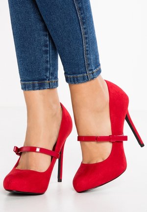 Rote Wildleder-Pumps mit Mary Jane-Riemen und einem glänzenden Schleifenakzent. Das Design verfügt über eine spitze Zehenform und einen Stiletto-Absatz.