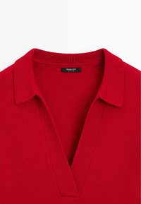 Czerwony, dziany sweter z szerokim dekoltem w kształcie litery V i prążkowanym kołnierzem, z widoczną czarną metką marki w okolicy kołnierza.