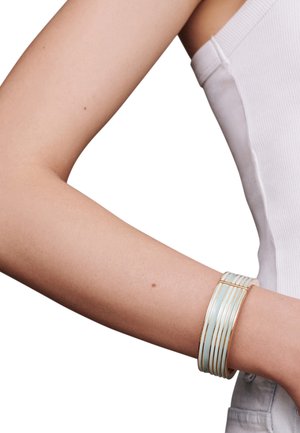 Gold-tone cuff bracelet featuring alternating light blue and white bands, smooth texture, and a sleek, curved design.