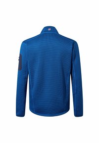 Blaues langärmliges Jackett aus strukturiertem Gewebe, mit hohem Kragen und kontrastierenden dunkelblauen Ellbogenpatches; zeigt dezente Logo-Details am Hals.